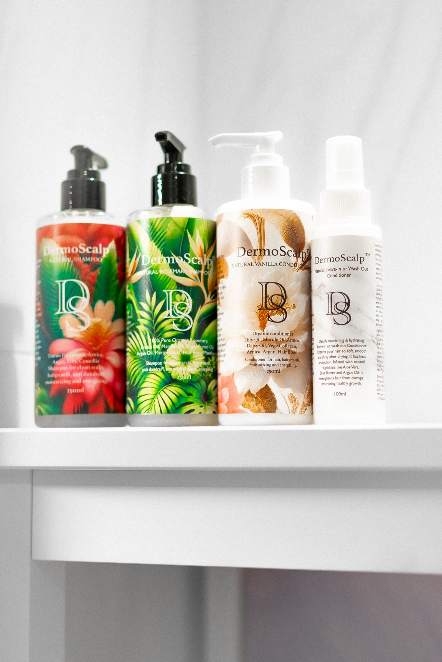 Collection of Design Essentials hair care products with tropical and floral packaging displayed on white shelf.
