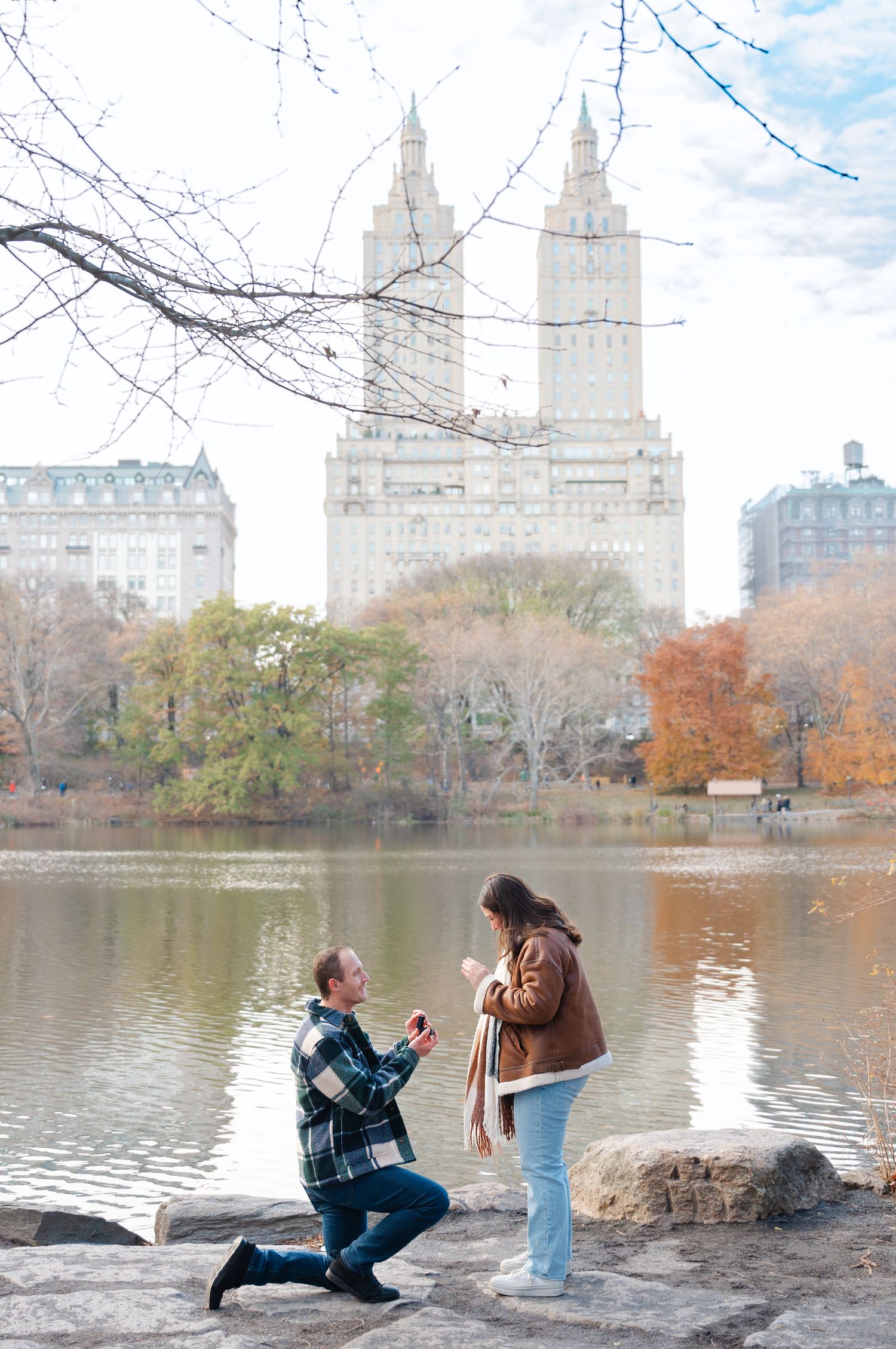 A romantic couple shares tender moments in an autumn park setting during an engagement photo session.