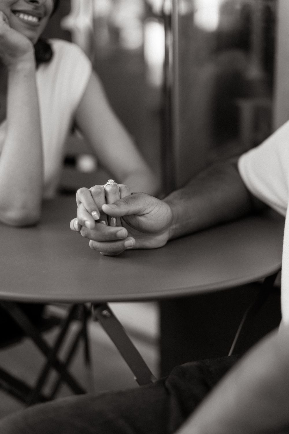 Artistic black and white detail shots of hands resting on a table surface.