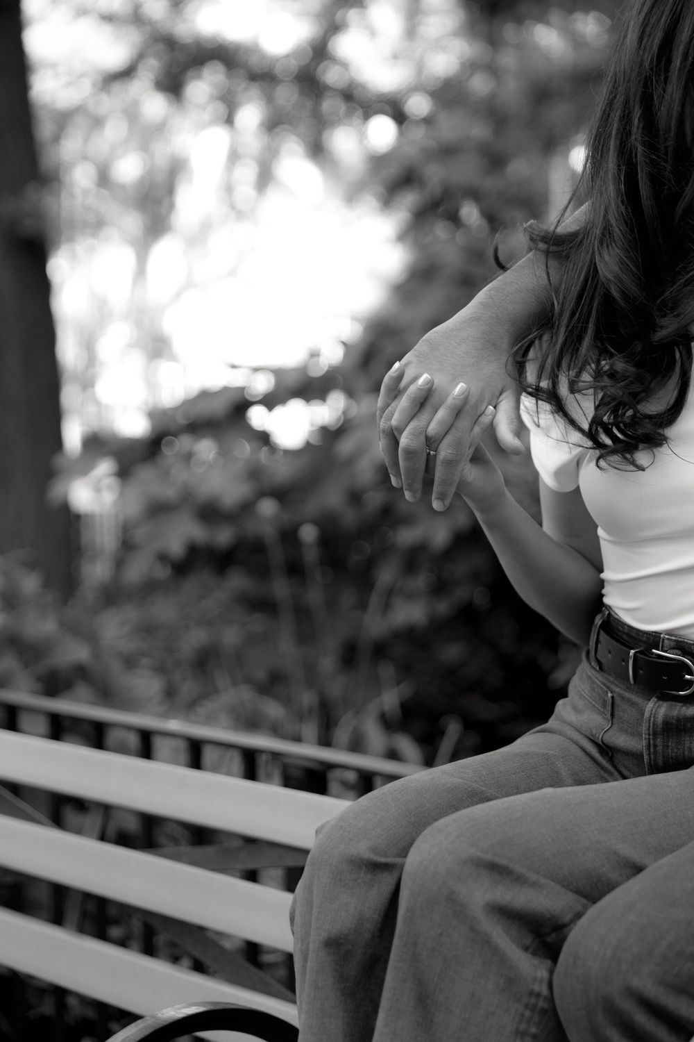 Close-up black and white photo of two people sitting close together on a bench.