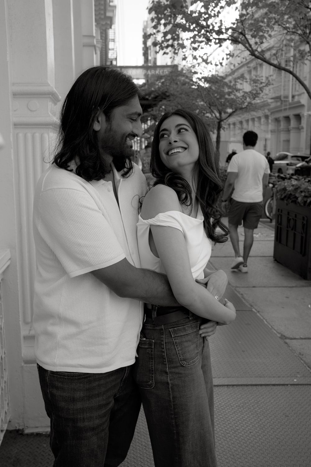 A couple shares playful and intimate moments together in a series of black and white photographs on a city street.