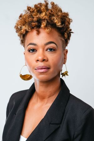 Professional headshot series showing warm expressions and curly copper hair against white background wearing black blazer.