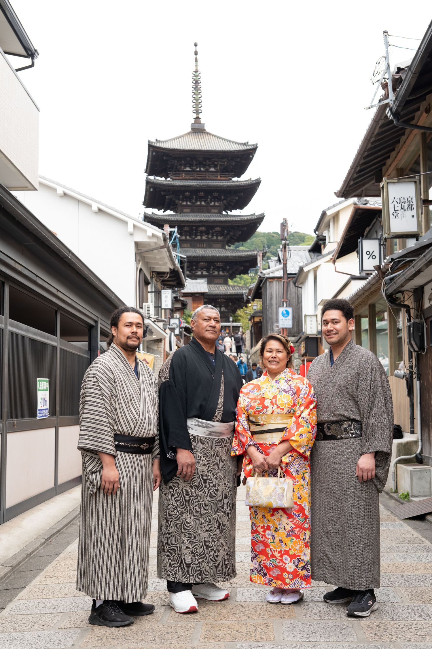 Family of four in traditional Japanese attire standing before a five-story pagoda.