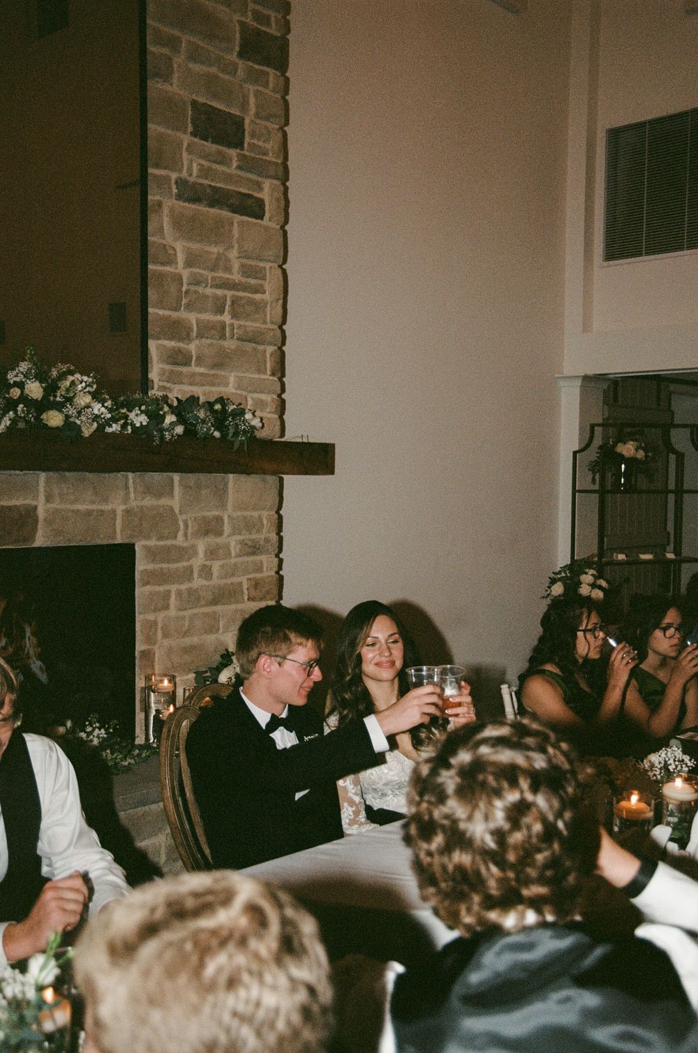 A crowded party scene showing people raising their glasses in a toast at what appears to be a celebration event.