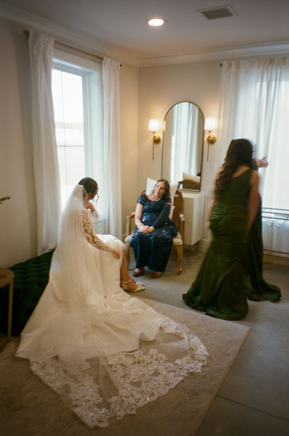 A series of indoor photos showing a white wedding dress with lace train against dark bridesmaid dresses in a light room.