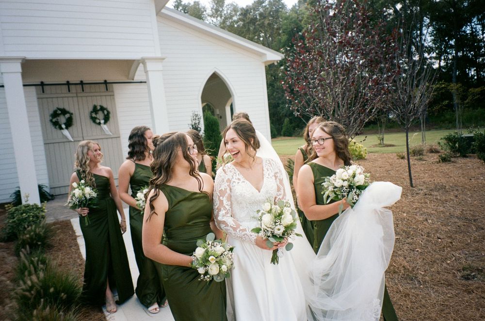 A group shares joyful moments during an outdoor wedding celebration at a white chapel venue.