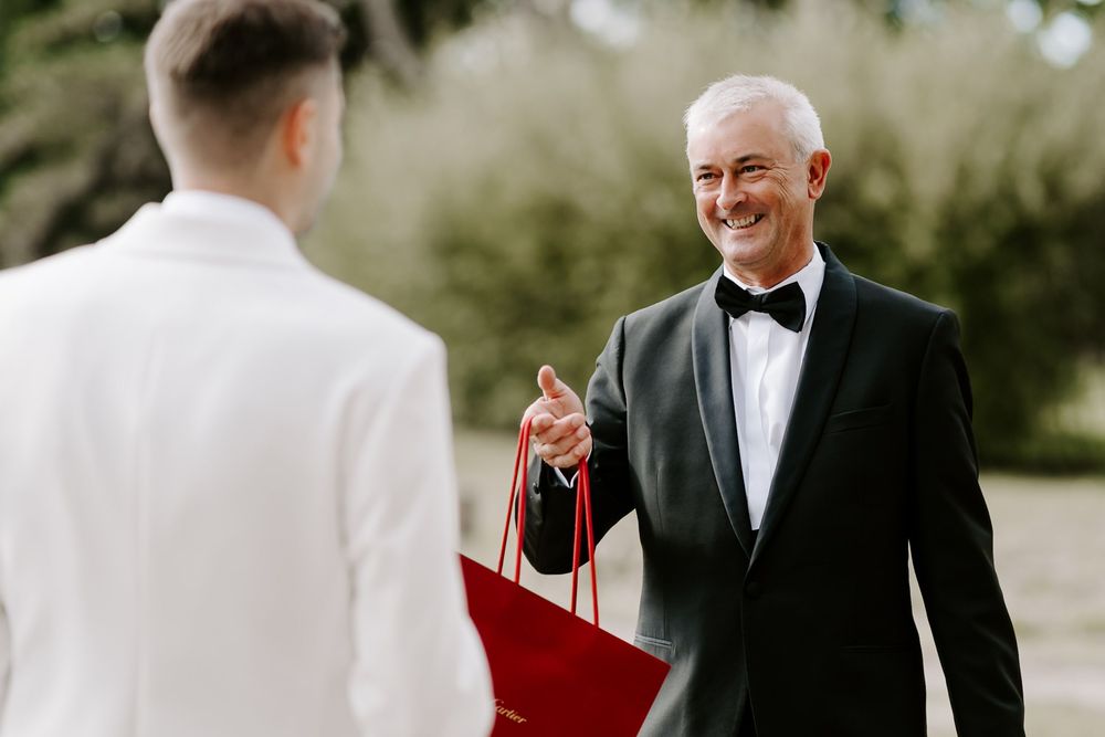 A couple in formal wedding attire shares a joyful moment together outdoors during their special day.