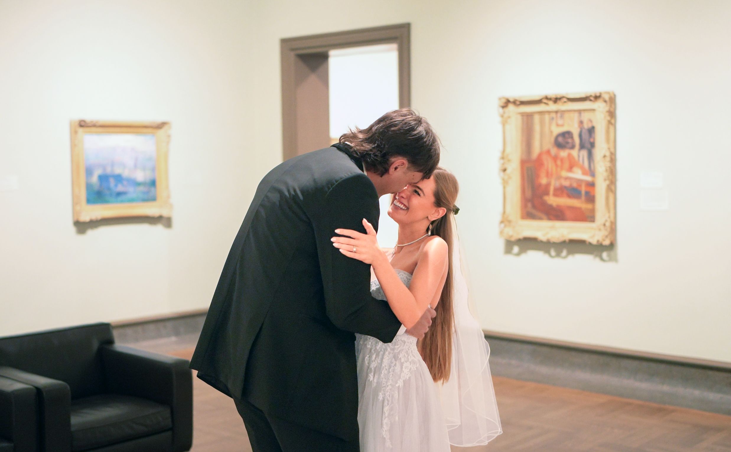 A newlywed couple shares an intimate moment in a quiet art gallery surrounded by framed paintings in Columbus Museum Of Art