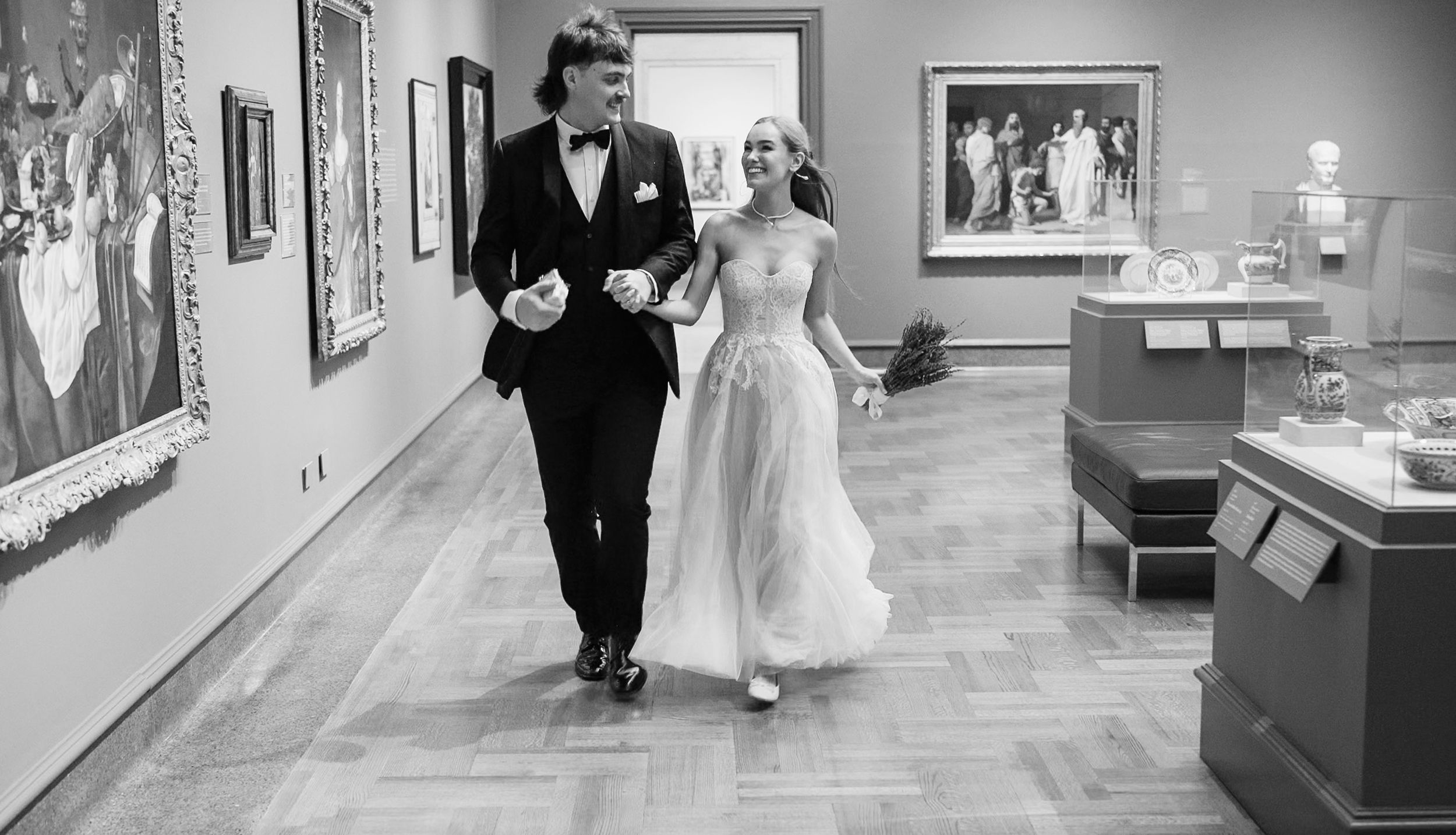 A bride and groom walk together through an elegant museum gallery in Columbus Museum Of Art
