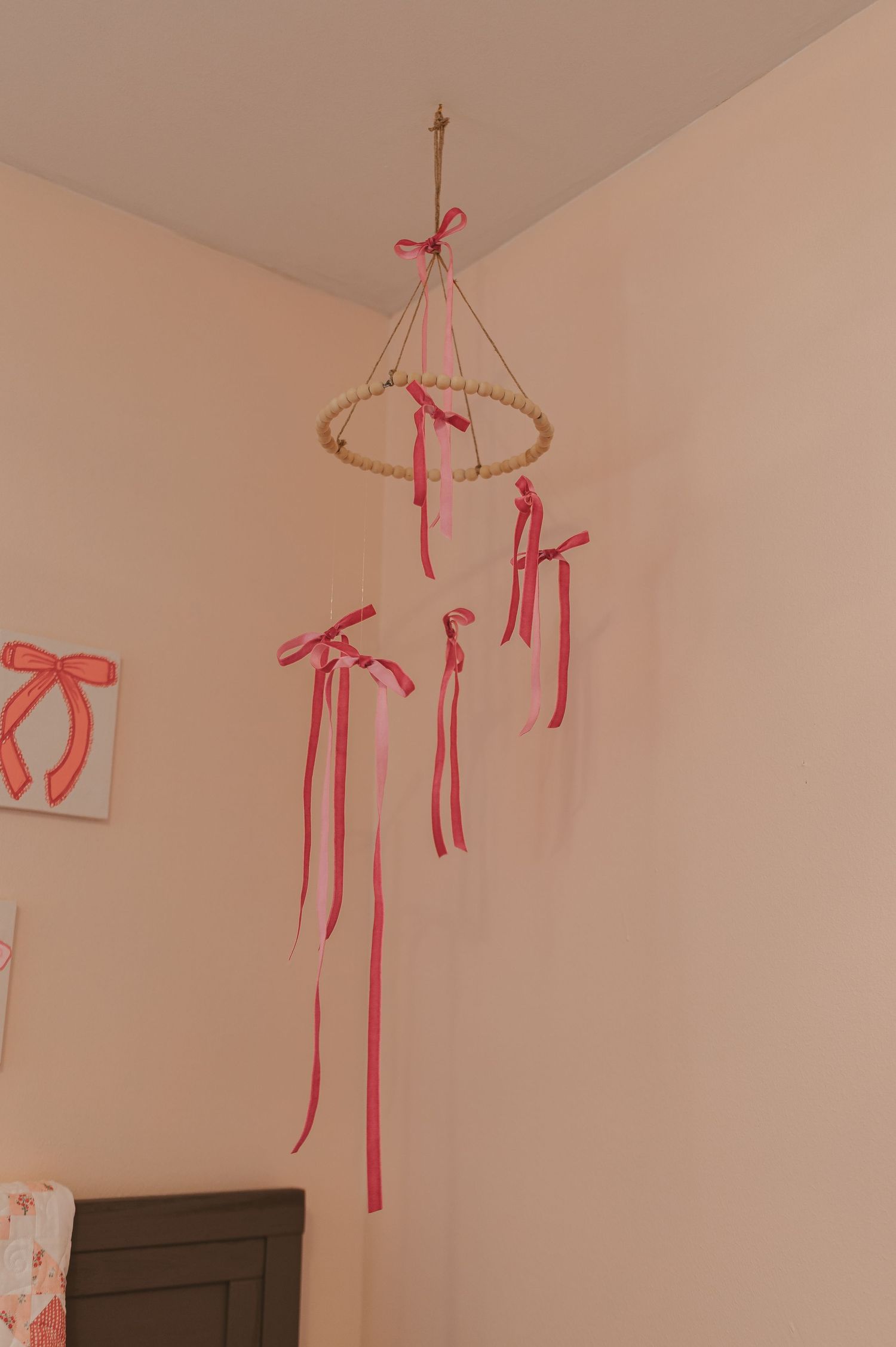 Pink bow decorations hanging from ceiling in nursery room.