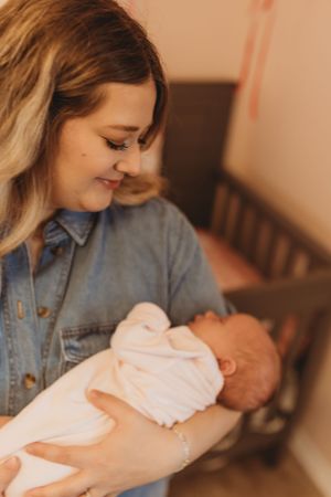 A gentle moment of bonding with a newborn baby wrapped in white.