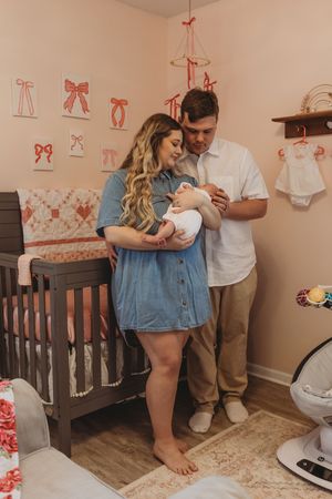 A nursery room scene with pink bow decorations and wooden furniture.