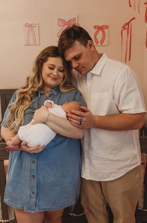 An intimate moment in a nursery decorated with pink bows and wooden furniture.