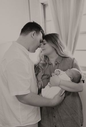 A black and white photo capturing a tender moment between parents and their newborn baby.