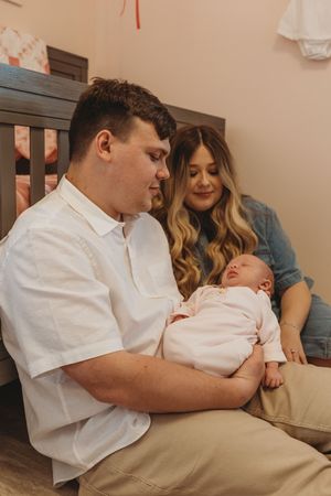 Parents share a special moment in the nursery while holding their sleeping newborn baby.