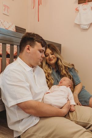 A peaceful moment in the nursery as parents bond with their sleeping newborn baby.