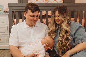A candid family moment in the nursery as parents lovingly gaze at their sleeping newborn.