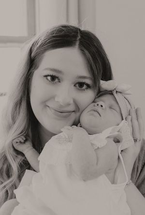 A series of intimate black and white close-up photos showing tender moments with a baby in white clothing.
