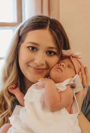 Sweet candid moment between family members with baby in white dress.