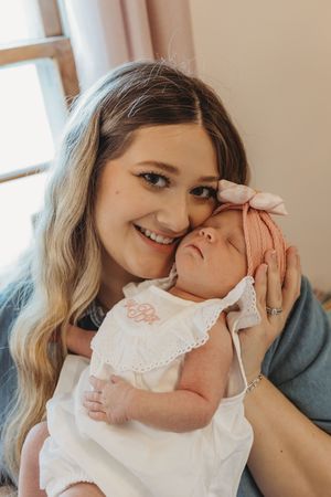 Tender moments captured between parent and baby wearing a delicate white lace dress.