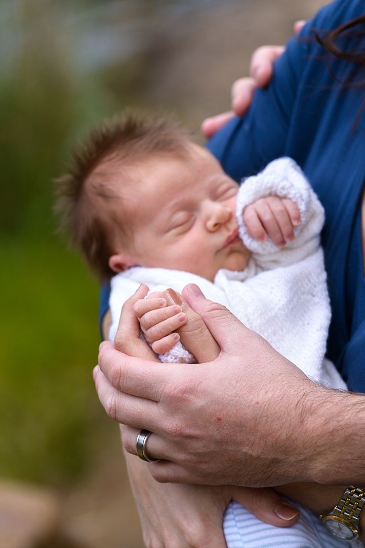 A newborn baby cradled in his mums arms dressed in a white hand knitted cardigan - Kelly Chapman Photographer Perth