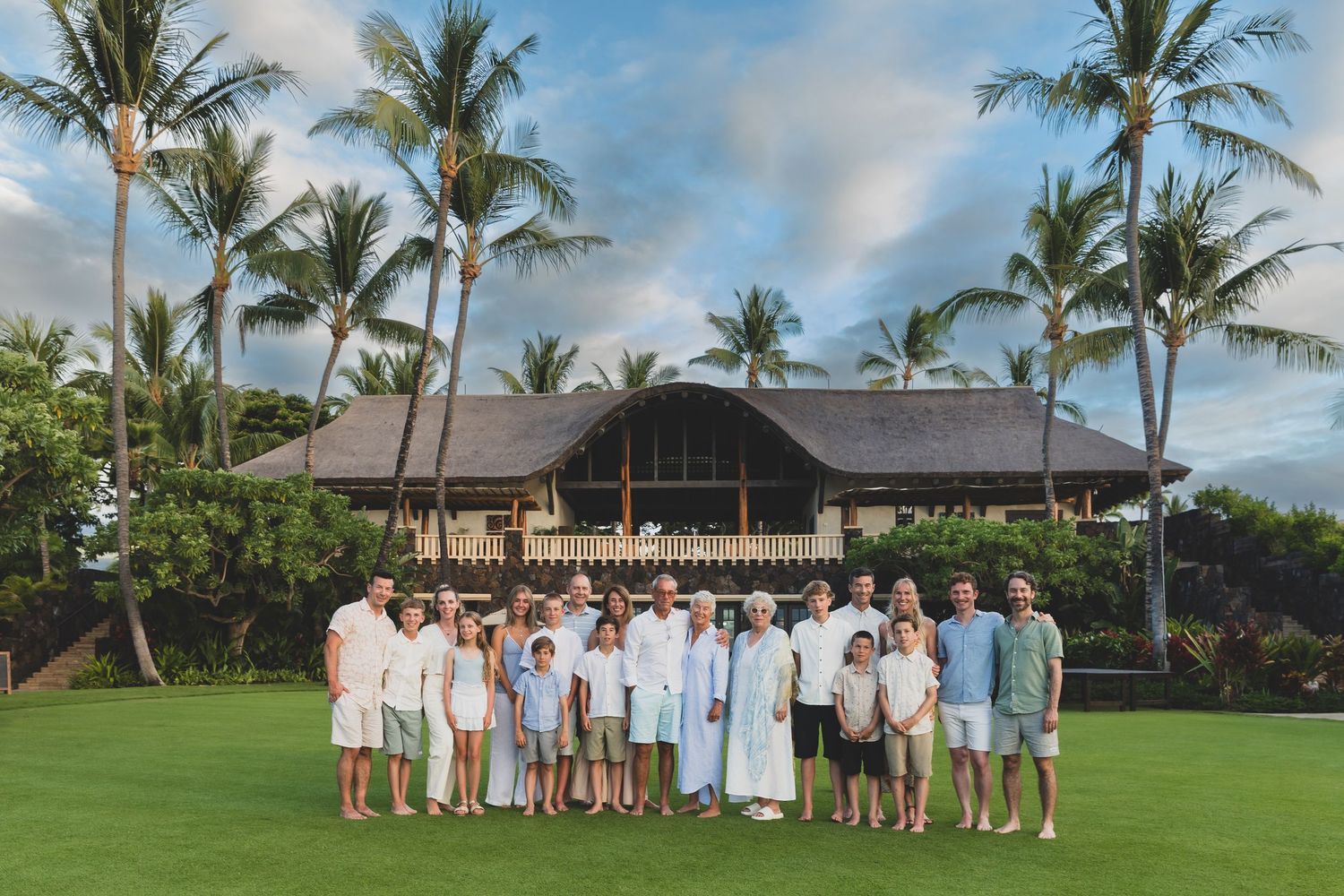 Family group poses casually together under tall palm trees in a tropical setting during golden hour.