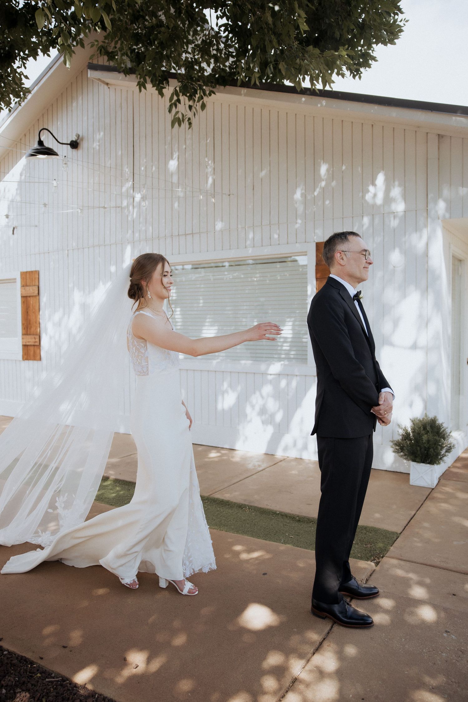 A sequence of photos showing a couple sharing a playful first look moment outside a white building.