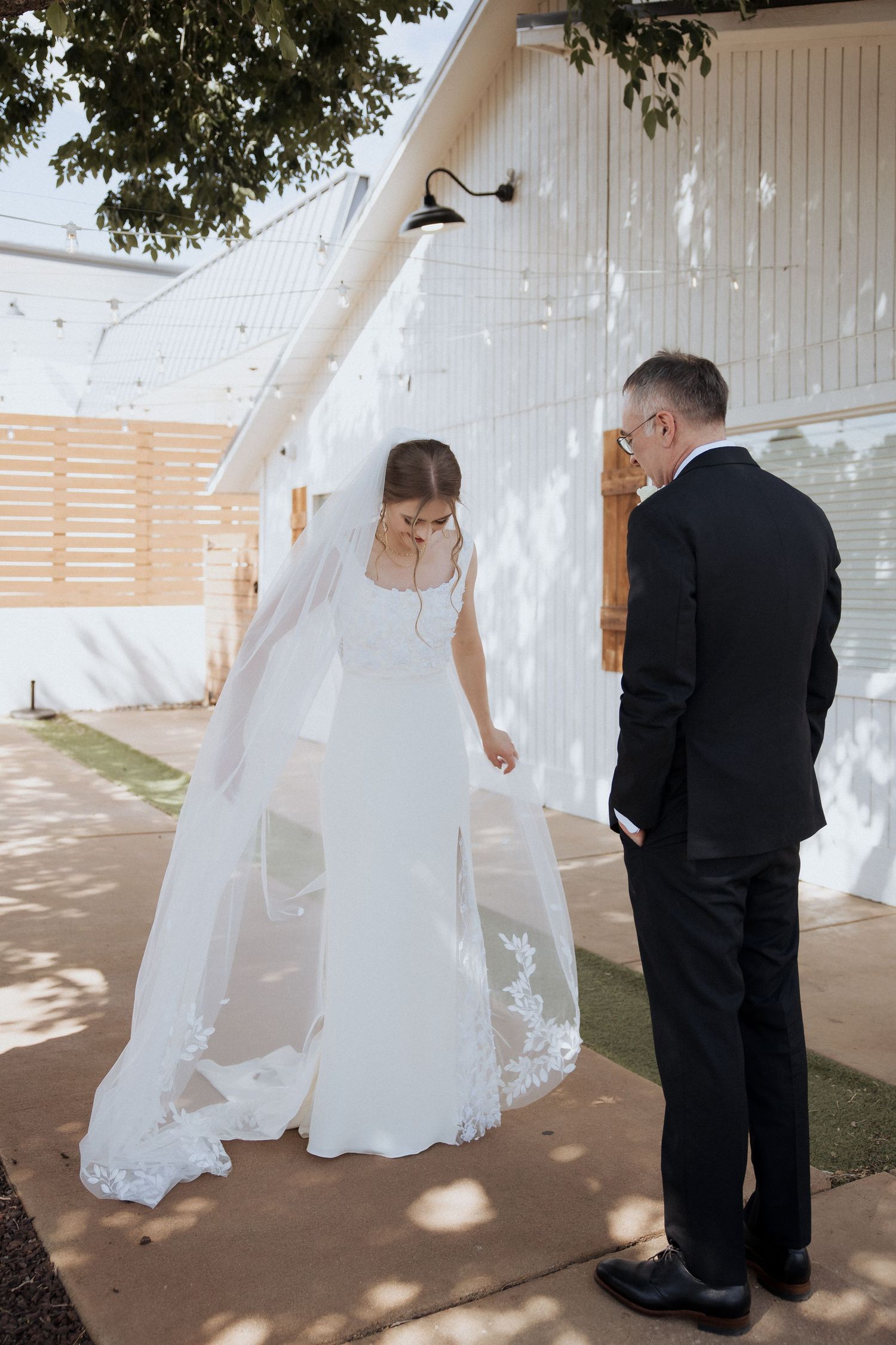 A romantic first look moment between a bride in white and groom in black during an outdoor wedding ceremony.