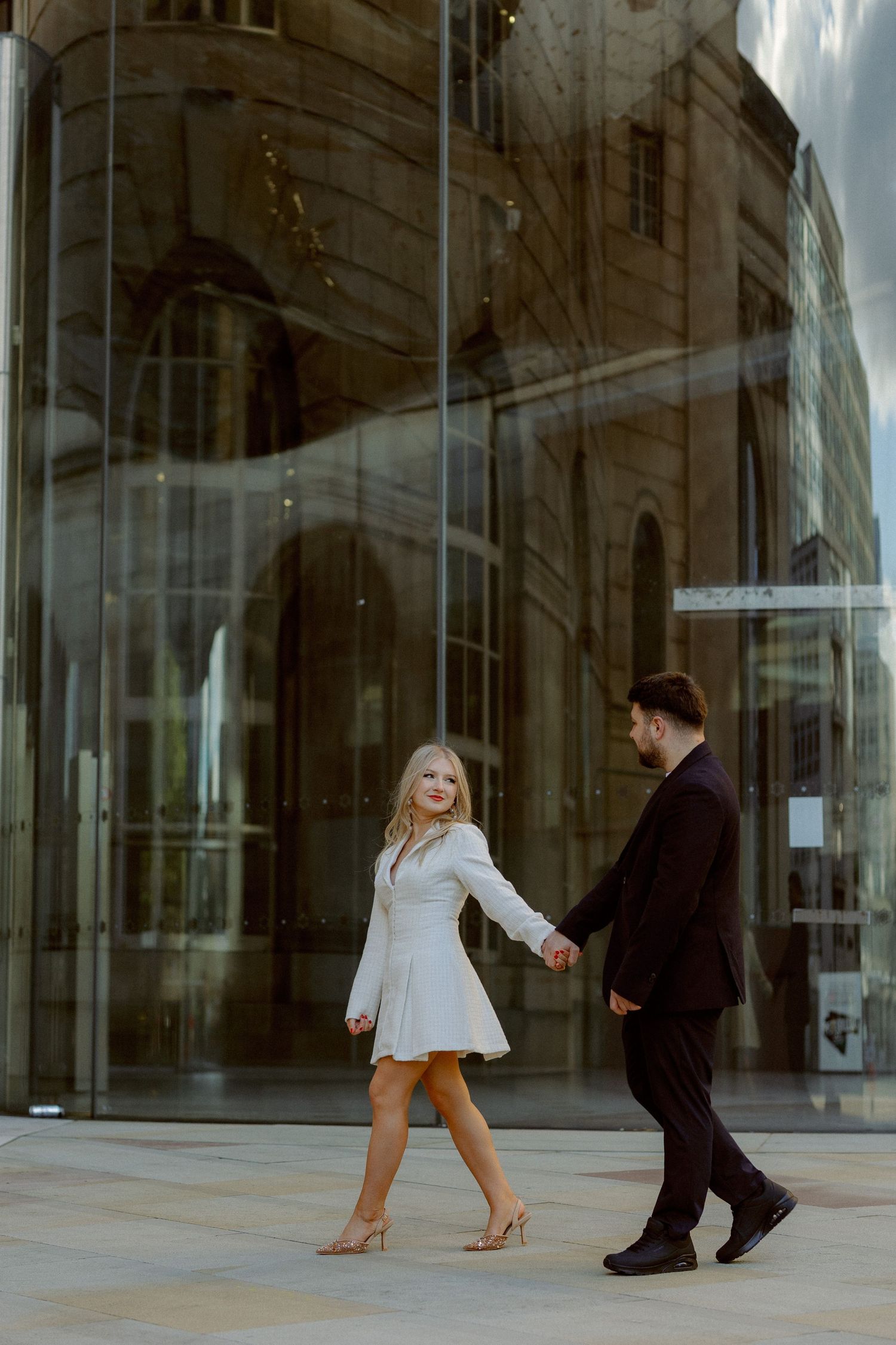 Couple walking through an art gallery with orange walls displaying framed paintings.