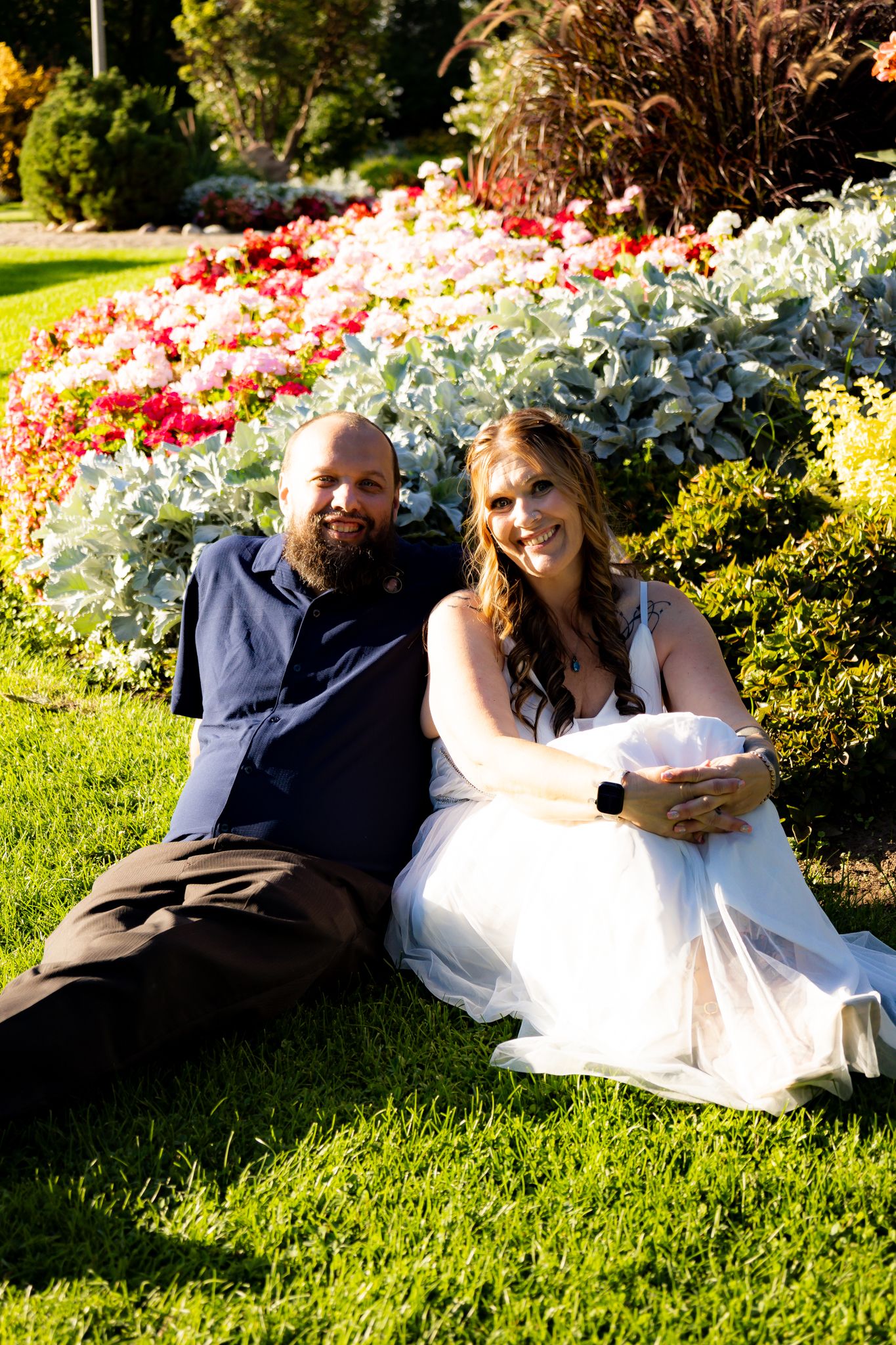 Wedding couple relaxing on grass near colorful flower garden.