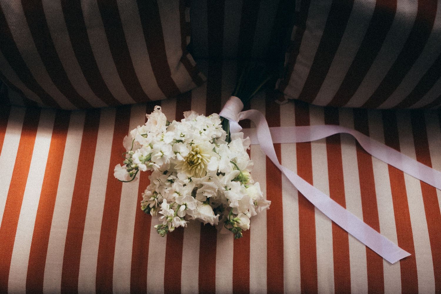 Elegant wedding reception setup with striped canopy, white floral arrangements, and romantic lighting for an outdoor celebration.