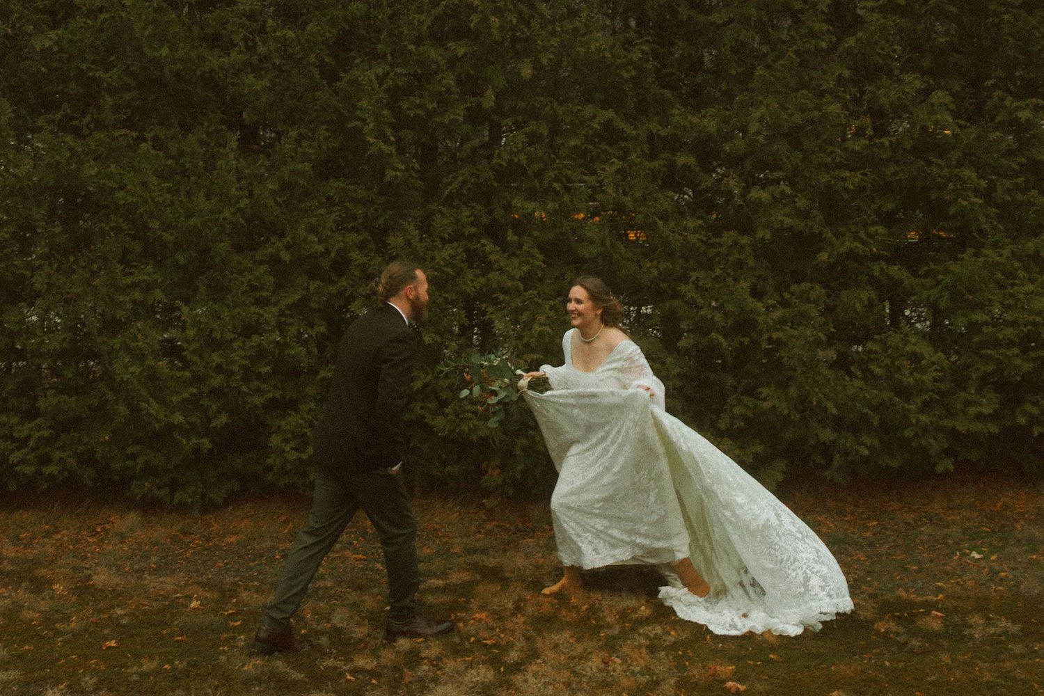 A flowing white wedding dress twirls dramatically in a dimly lit outdoor garden setting. stark, vintage wedding