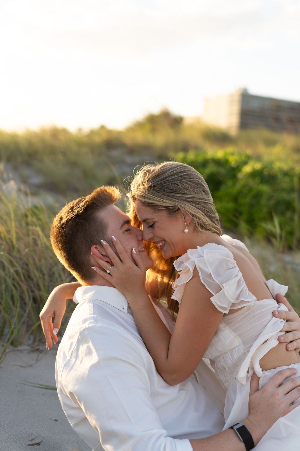 A tender beach moment captured in sequence showing a loving embrace against coastal vegetation.