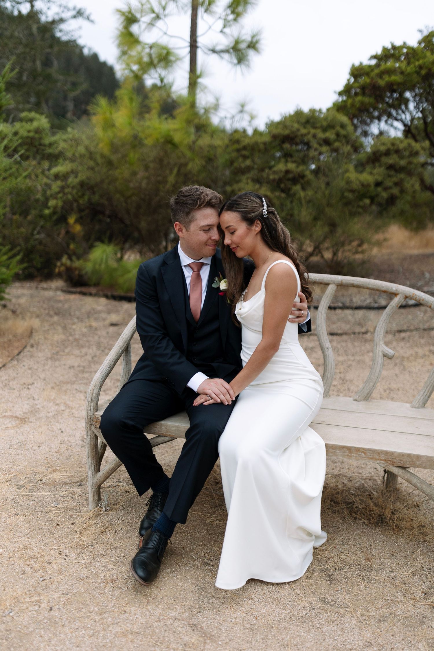 Intimate wedding portraits captured on rustic wooden benches in natural setting.