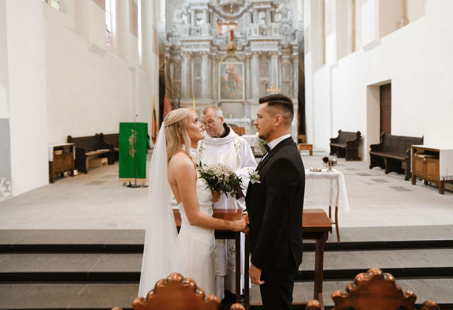 Couple shares an intimate moment during their wedding ceremony in a bright church sanctuary.