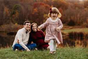 Family enjoying a warm autumn day together in a grassy field during golden hour.