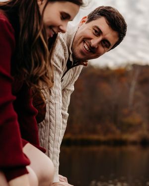 A couple in autumn attire shares a tender moment outdoors during a fall photoshoot.