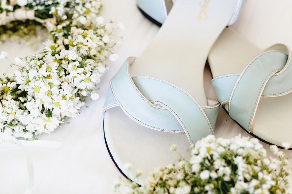 Delicate white baby's breath flowers arranged with pale blue high heel shoes on a white background.