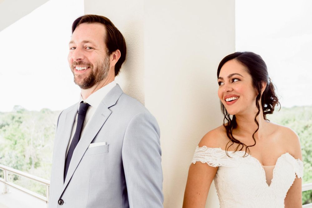 A bride and groom share joyful laughter during their wedding day photoshoot.