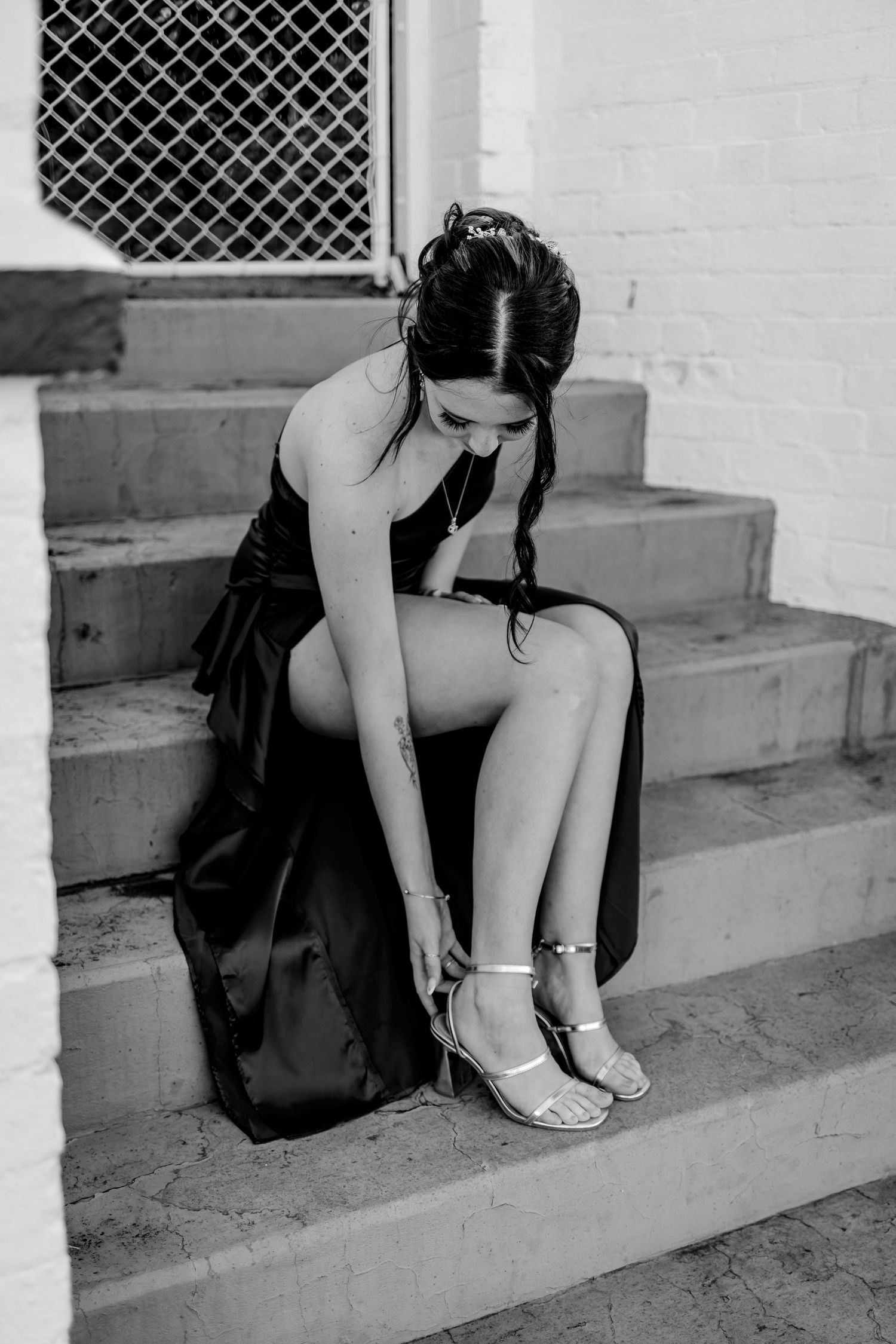 A series of black and white photos showing someone sitting on concrete steps adjusting their shoes.