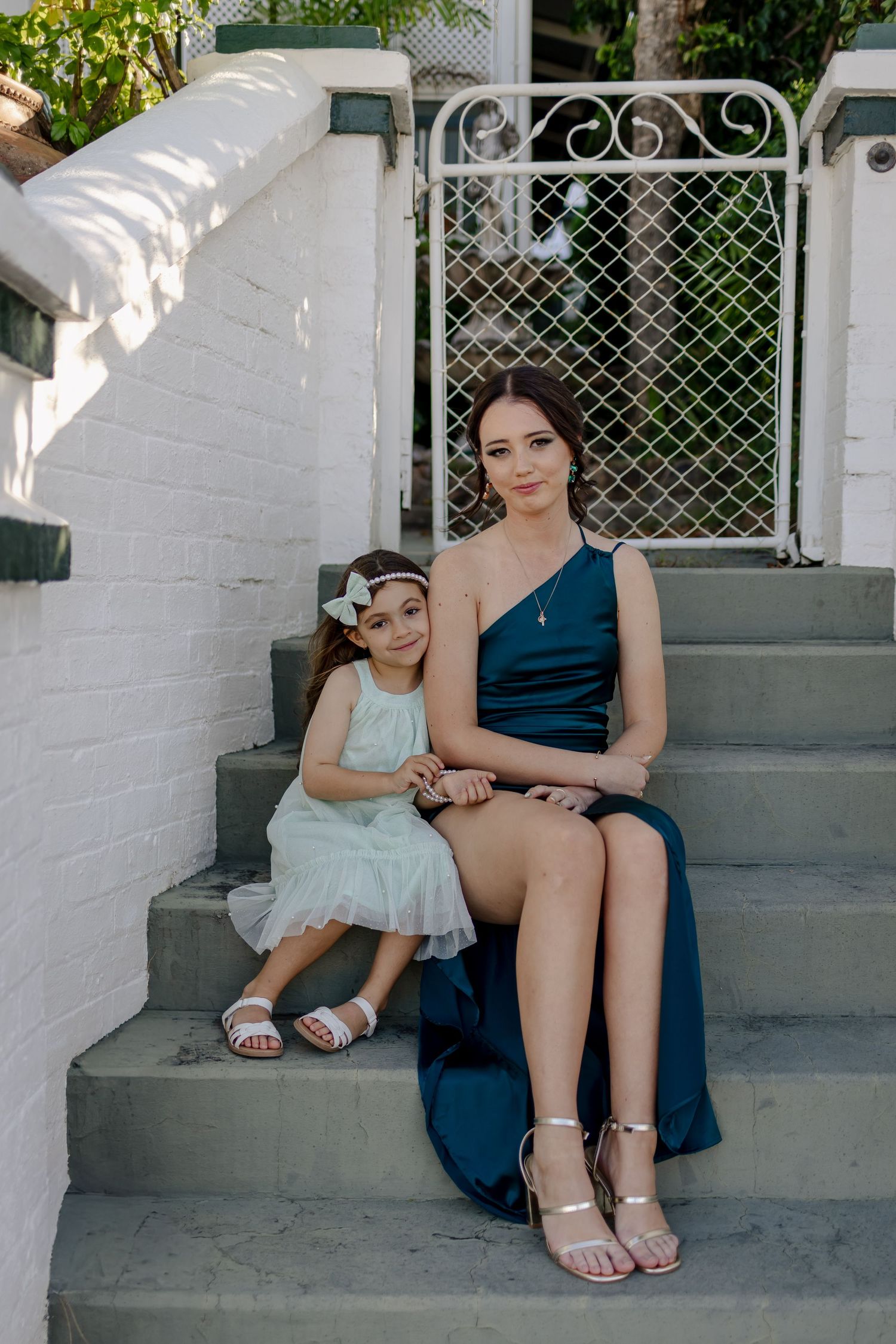 A mother and young child sit together on white concrete steps, captured in a series of candid moments.