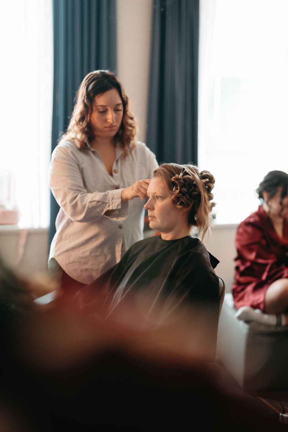 A series of images showing someone getting their hair styled and curled in a salon setting.