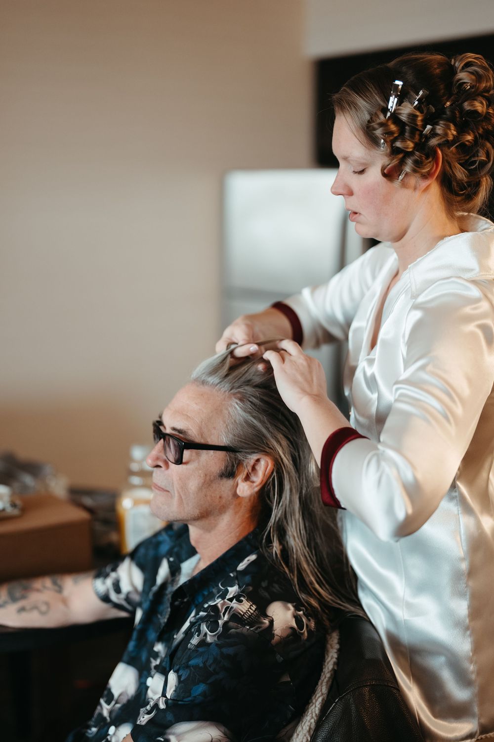 A hairstylist wearing white works on styling a client's long hair in a salon setting.
