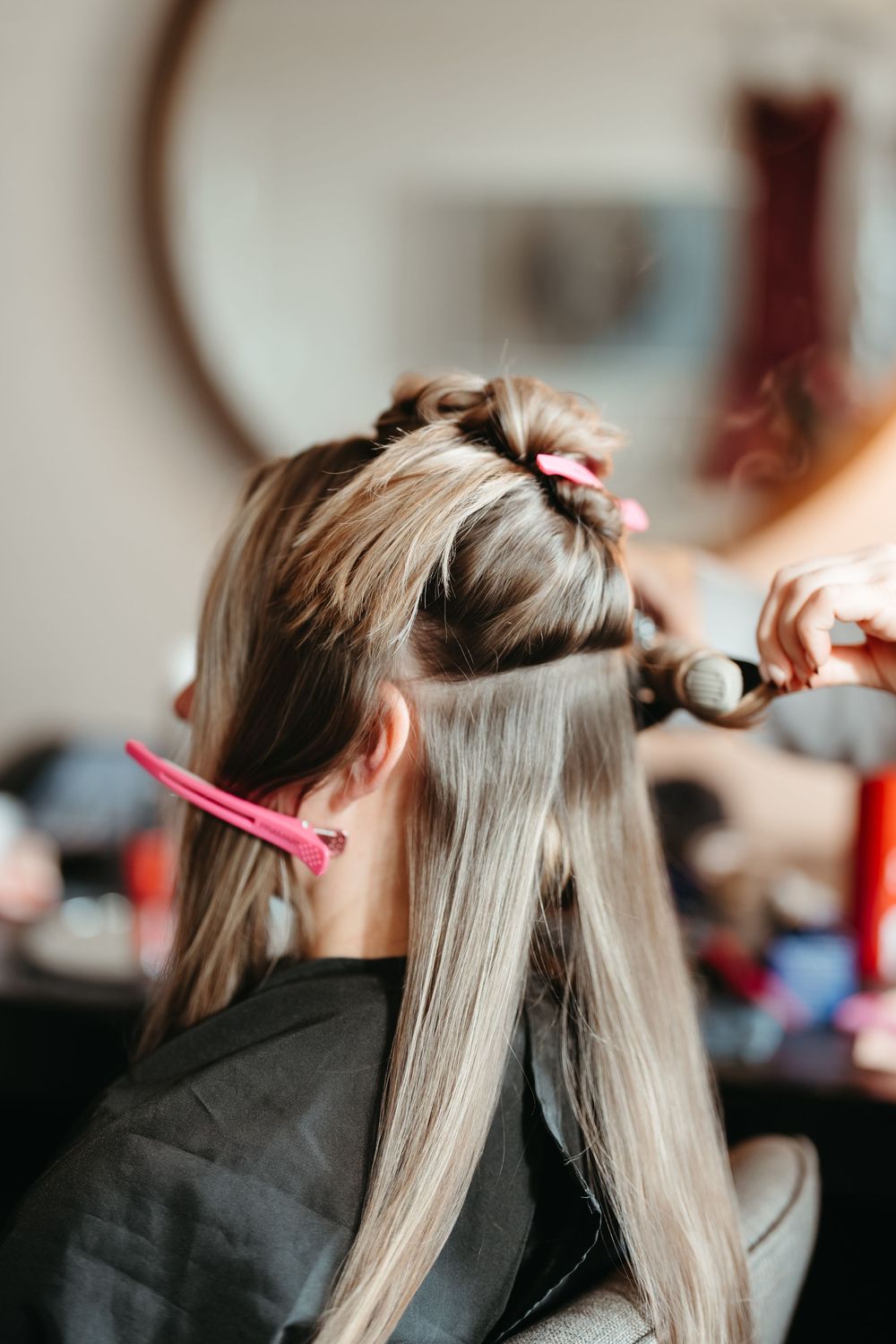 Hairstylist sections and styles long blonde hair in a professional salon setting.