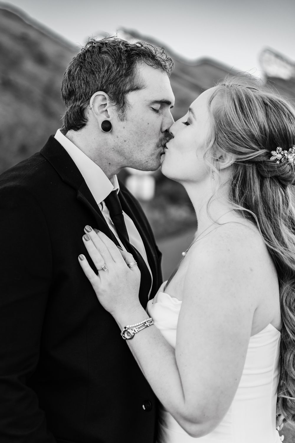 Black and white romantic wedding photos show intimate kisses between newlyweds in an outdoor setting.