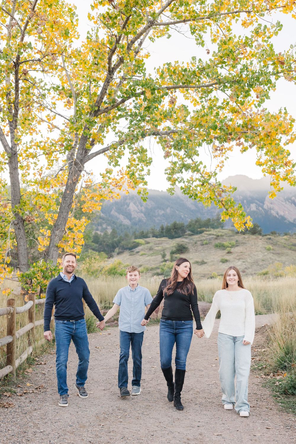 A group walking together on a dirt path with autumn trees and mountains in the background.