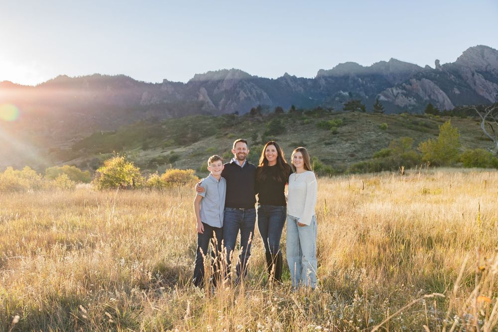 A scenic mountain landscape with rolling fields and dramatic peaks in the background.