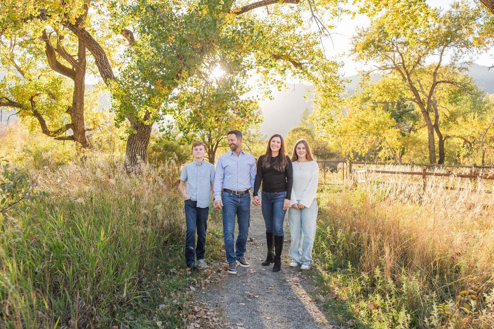 A group walks together on a path through golden autumn trees during sunset creating a warm family portrait.