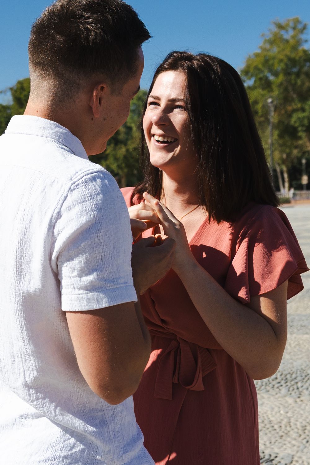 A couple shares an intimate moment outdoors while wearing coordinated pink and white outfits.