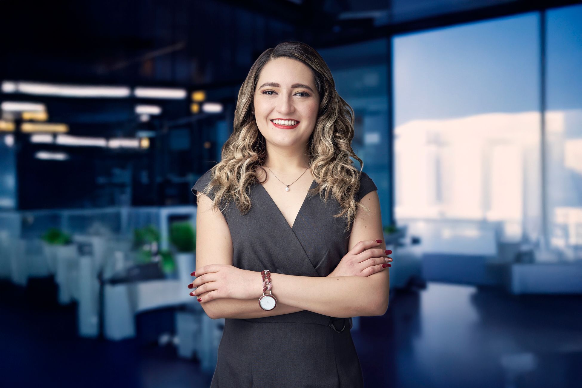Fotografía de mujer ejecutiva sonriendo con brazos cruzados en entorno corporativo moderno estilo Santa Fe.